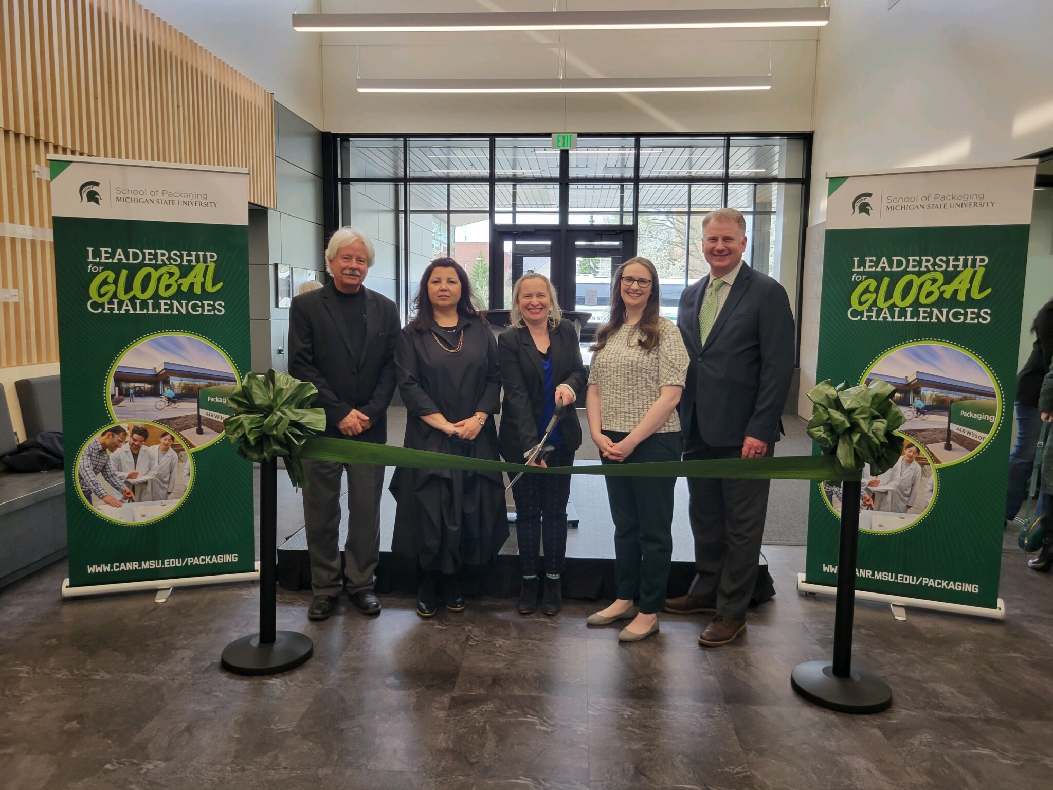 TMP staff holding scissors and cutting ribbon at MSU